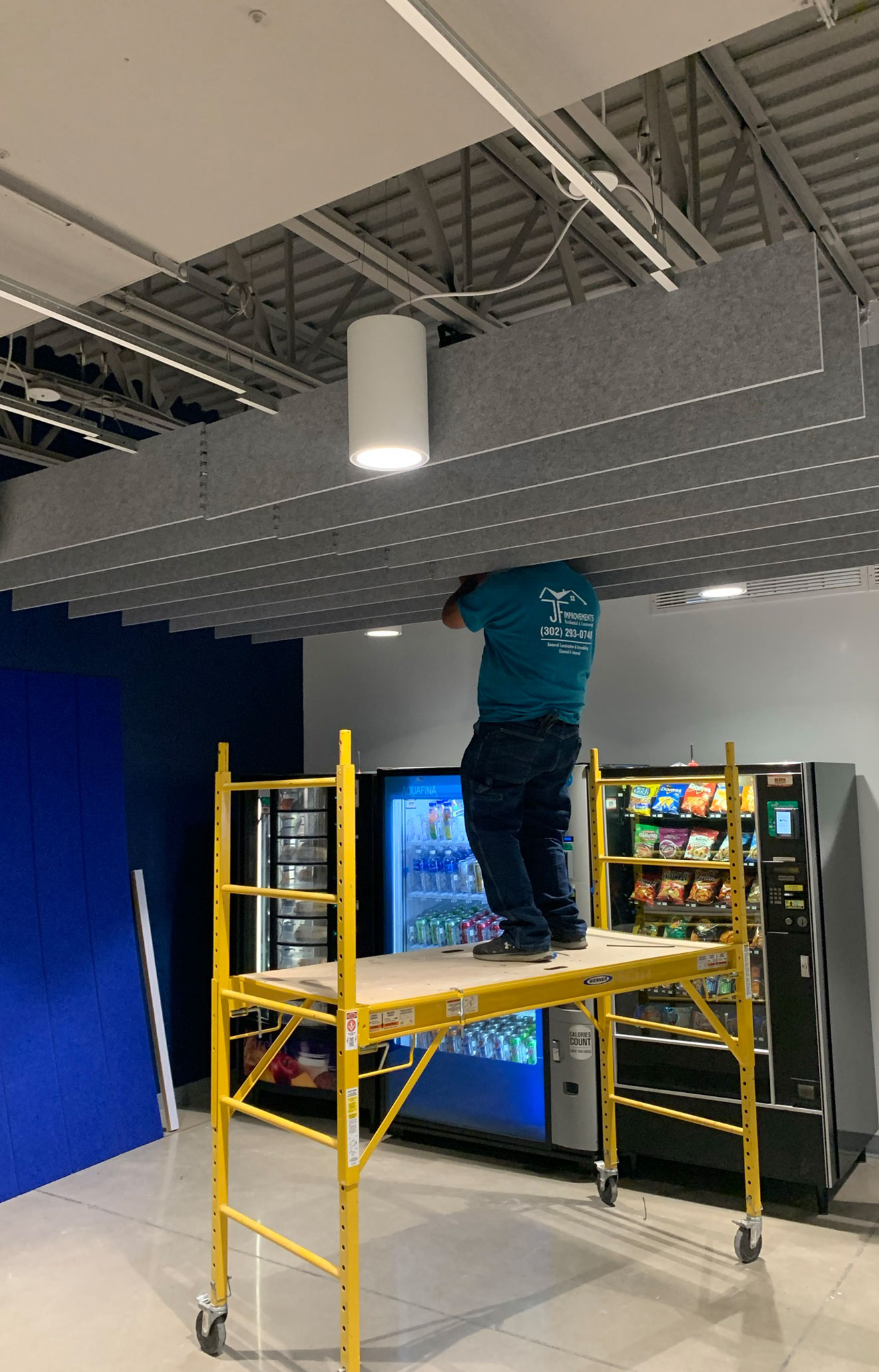 Worker installing sound installation panels standing on yellow lift